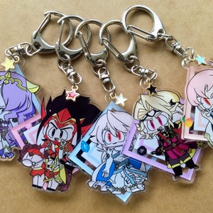May include: Six colorful anime character keychains with silver key rings. Each keychain features a different character with a unique design and a star-shaped charm.