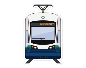Puede incluir: Un tren ligero de color blanco y azul con la palabra "UNIVERSITY" en la parte delantera. El tren tiene un parabrisas negro y un techo negro.
