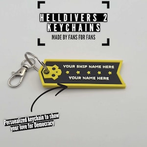 Pode incluir: Um chaveiro amarelo e preto com o texto "HELLDIVERS 2 KEYCHAINS MADE BY FANS FOR FANS". O chaveiro tem um design de caveira e espaço para personalização com "YOUR SHIP NAME HERE" e "YOUR NAME HERE". Inclui um fecho prateado.