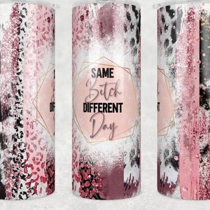 May include: A stainless steel tumbler with a pink, black, and white design. The tumbler features a leopard print pattern, glitter accents, and the text "SAME BITCH DIFFERENT DAY" in a geometric frame. The tumbler is designed to hold cold or hot beverages.