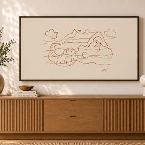 Puede incluir: Una impresión de arte mural rectangular que presenta un dibujo lineal minimalista en color marrón de una sirena nadando en el agua con nubes encima. La obra está expuesta en un marco oscuro e incluye una pequeña firma en la esquina inferior.