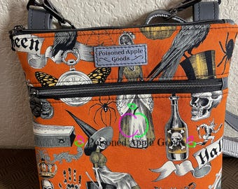 Pode incluir: Uma pequena bolsa de ombro laranja e preta com fecho de correr. A bolsa apresenta uma estampa temática de Halloween com imagens de uma bruxa, uma caveira, uma aranha, um corvo, uma garrafa, um relógio e uma coroa. A bolsa tem uma guarnição de couro cinza e uma alça preta. A bolsa tem uma etiqueta que diz "Poisoned Apple Goods".