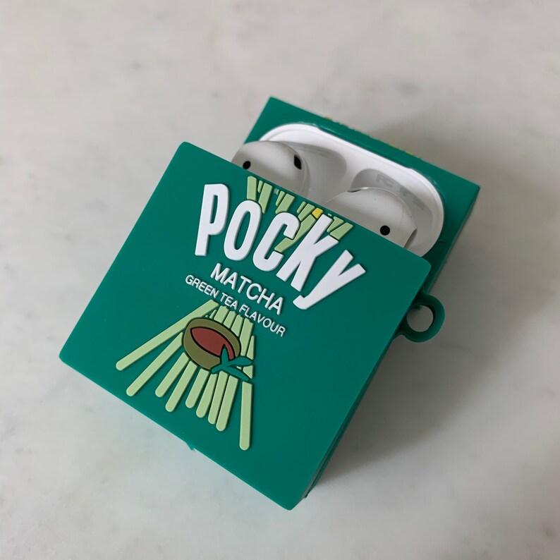 May include: Green silicone AirPods case shaped like a Pocky Matcha box. The case is open, revealing white earbuds. The box design includes the word "Pocky" in white, along with "Matcha Green Tea Flavour" text and a graphic of Pocky sticks.