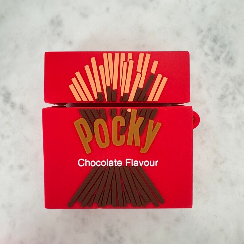 May include: A red case for wireless earbuds, designed to resemble a Pocky chocolate snack box. The case features the word "Pocky" in gold lettering, with the words "Chocolate Flavour" below. The top of the case is open, revealing a design of biscuit sticks.