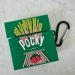 May include: Green Pocky-themed AirPod case with a black carabiner clip. The case features the Pocky logo in white, Japanese text, and a strawberry flavor graphic. The top of the case has a design of Pocky sticks.