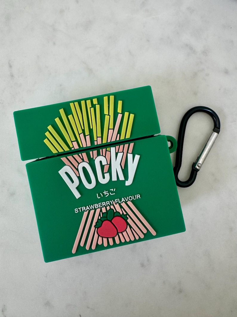 May include: Green Pocky-themed AirPod case with a black carabiner clip. The case features the Pocky logo in white, Japanese text, and a strawberry flavor graphic. The top of the case has a design of Pocky sticks.