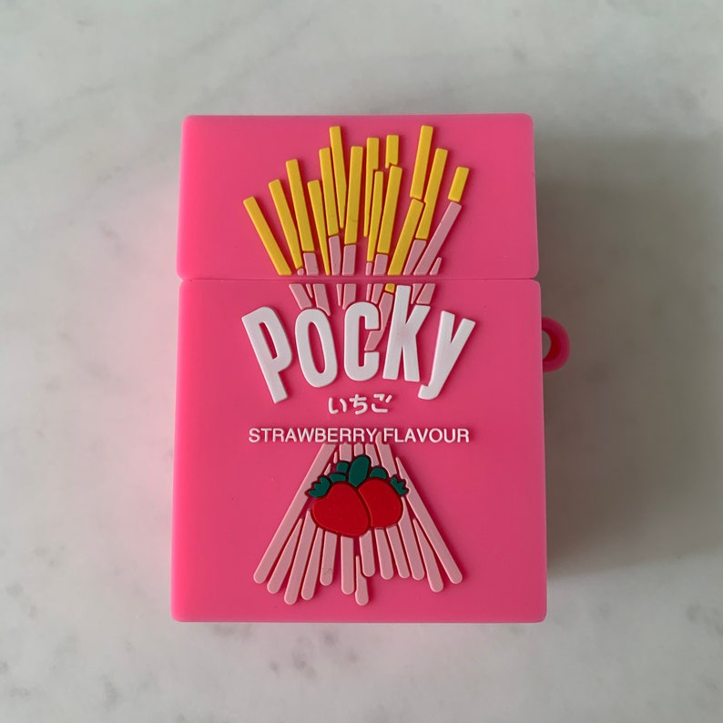 May include: A pink case featuring a Pocky strawberry flavor design. The case has a rectangular shape with a hinged lid. The design includes the word "Pocky" in white, Japanese characters, and a strawberry graphic.