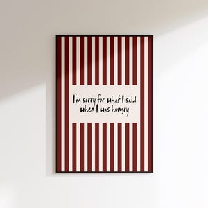 May include: A framed print with a red and white striped background. The print features the text "I'm sorry for what I said when I was hungry" in black script on a white rectangular block.