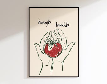 May include: A framed art print featuring a red tomato held in two hands, with the words "tomayto tomahto" above. The artwork is a minimalist line drawing style with a cream-colored background and black frame.
