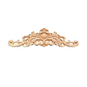 May include: A decorative wooden carving with intricate details, featuring a central oval shape surrounded by swirling floral patterns. The carving is a light brown colour and has a smooth, polished finish.