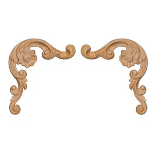 May include: A pair of ornate wooden decorative corner brackets with a floral design. The brackets are light brown in colour and have a carved, scroll-like pattern.