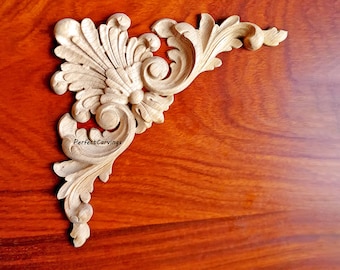 May include: A wooden corner ornament with intricate carvings in a light brown color. The ornament is on a dark brown wooden surface.