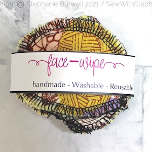 May include: A stack of reusable face wipes made from colorful fabric with a black zig-zag stitch around the edges. The wipes are packaged with a white label that reads "face-wipe" in pink cursive and "handmade - Washable - Reusable" in black text.