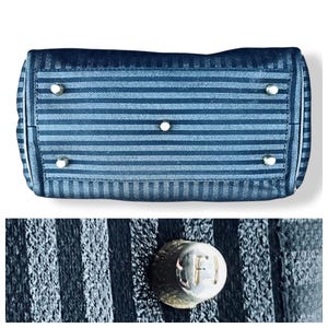 May include: Bottom view of a navy blue handbag with horizontal stripes. The bag has silver-toned feet and hardware. The close-up shows a silver stud with the letters "F" and "J" engraved on it.