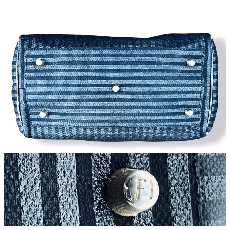 May include: Bottom view of a navy blue handbag with horizontal stripes. The bag has silver-toned feet and hardware. The close-up shows a silver stud with the letters "F" and "J" engraved on it.