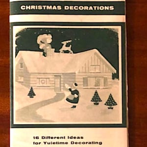 May include: A booklet titled CHRISTMAS DECORATIONS with the subtitle 16 Different Ideas for Yuletime Decorating. The cover features a dark green and white illustration of a house with a person on the roof, a reindeer, and a person in the yard.