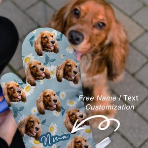 Puede incluir: Un guante de cocina azul claro con un patrón repetido de la cara de un Cocker Spaniel y margaritas blancas. El nombre "Nina" está impreso en el guante. También se ve el texto "Personalización gratuita de nombre/texto".