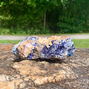 May include: A rough, natural rock with a blue and gold mineral formation. The rock has a rough, uneven surface and is a natural, unpolished specimen.