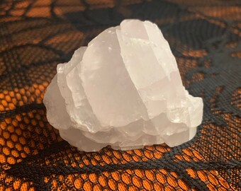 May include: A large, white, natural selenite crystal with a layered, stacked formation. The crystal has a smooth, polished surface and is translucent.