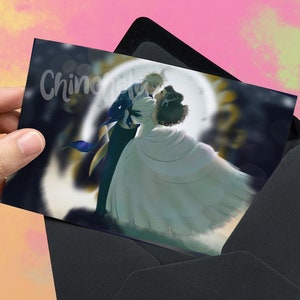 May include: A black envelope with a white card inside. The card features a couple in a romantic embrace, with the woman in a white dress and the man in a black suit. The background is a blurred image of a moon and stars.