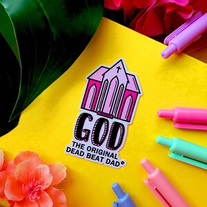 A sticker of a pink church with text that reads "GOD the original dead beat dad tm"