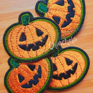 May include: Four orange and green embroidered pumpkin patches with black smiling faces.