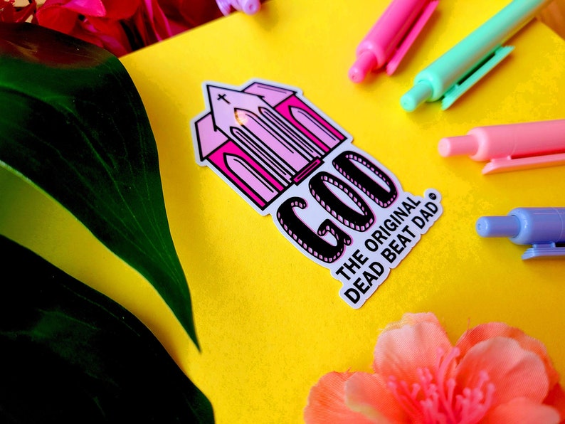 A sticker of a pink church with text that reads "GOD the original dead beat dad tm"