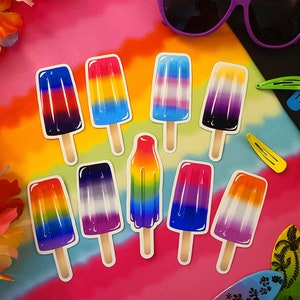 Puede incluir: Nueve pegatinas de polos de colores con diferentes diseños de banderas del orgullo. Las pegatinas están sobre un fondo tie-dye con otras decoraciones de temática veraniega.