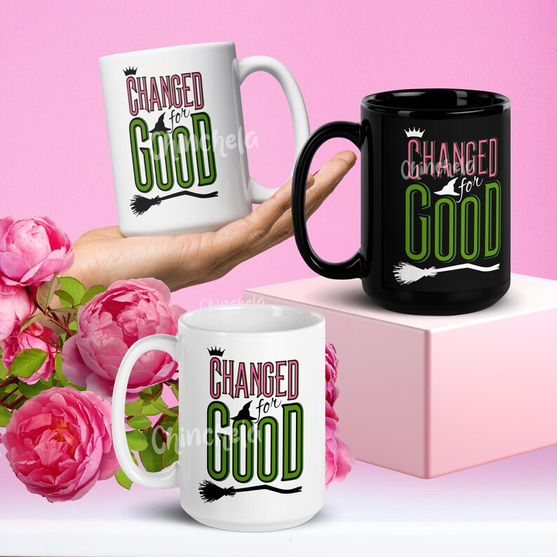 Pode incluir: Duas canecas de cer&acirc;mica com um design preto e branco. As canecas apresentam o texto "Changed for Good" com um gr&aacute;fico de chap&eacute;u de bruxa e vassoura. Uma caneca &eacute; branca com texto rosa e a outra &eacute; preta com texto branco.
