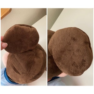 May include: A brown plush toy with a brown hair bun on top of its head. The toy is wearing a blue shirt.
