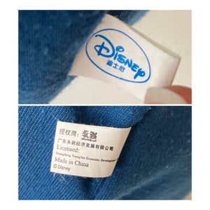 May include: White tag with the word "Disney" in blue lettering and the word "Authorized" in Chinese characters. Below the tag is a white tag with black text that reads "Authorized: YongJun, Guangdong YongJun Economic Development Co., Ltd., Licensed: Made in China, &copy;Disney."