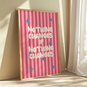Puede incluir: Una impresión artística enmarcada con un fondo a rayas rosas y rojas. La impresión presenta el texto "NOTHING CHANGES IF NOTHING CHANGES" en letras blancas con burbujas, con acentos de estrellas azules. El marco es de color marrón claro.