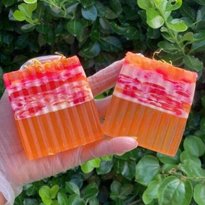 Puede incluir: Dos barras de jab&oacute;n hechas a mano con un dise&ntilde;o en capas. El jab&oacute;n es naranja, blanco y rosa. El jab&oacute;n est&aacute; hecho con ingredientes naturales.