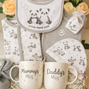 May include: A baby gift set with panda bear designs, including a bib, onesie, hat, and other items. The set includes two white mugs with the text "Mummy's Mug" and "Daddy's Mug". The items are presented in a gift box.