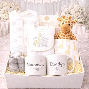 May include: A baby gift hamper containing baby clothes, a bib, a giraffe soft toy, a blanket, two mugs reading "Mummy's Mug" and "Daddy's Mug", and baby booties. The items are in white and cream colours.