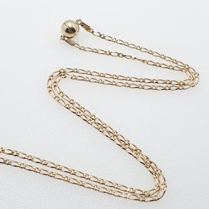 May include: A gold chain necklace with a magnetic clasp. The chain is made of multiple strands of small, linked gold pieces.
