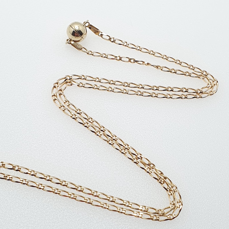 May include: A gold chain necklace with a magnetic clasp. The chain is made of multiple strands of small, linked gold pieces.