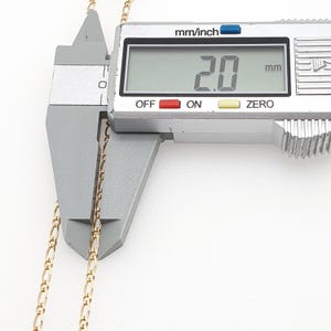 May include: A close-up of a gold chain being measured with a digital caliper. The caliper reads 2.0 mm.
