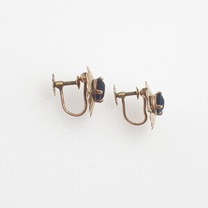 May include: A pair of gold-tone clip-on earrings with black stones.