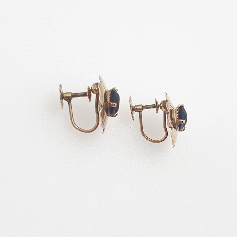 May include: A pair of gold-tone clip-on earrings with black stones.