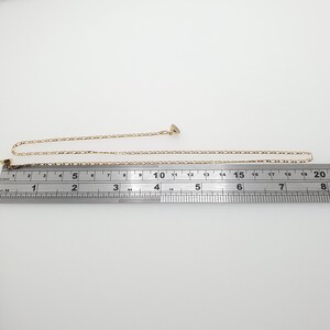 May include: A gold chain necklace measuring 18 inches in length. The chain is a delicate, fine link style.