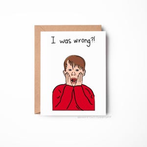 Puede incluir: Una tarjeta de felicitación con un sobre marrón. La tarjeta presenta una ilustración de dibujos animados de una persona sorprendida con una camisa roja, con el texto "I was wrong?!". La tarjeta está sobre un fondo blanco.