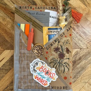 K&ouml;nnte beinhalten: Ein handgefertigtes Geschenkpaket zum Thema B&uuml;cher mit den Worten "North Carolina Book Review" und "Coming of Age". Enth&auml;lt einen Teebeutel, Haftnotizen, ein Wachssiegel und einen Aufkleber mit der Aufschrift "Books change the world".