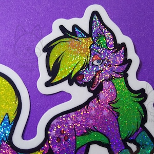 Puede incluir: Una pegatina colorida y brillante de un lobo de dibujos animados con pelaje verde y morado, una melena amarilla y una cola azul y rosa.