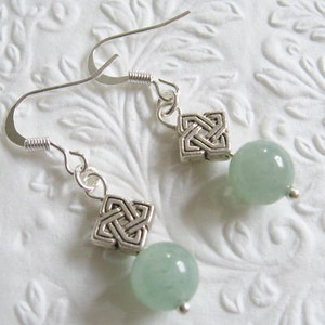 Könnte beinhalten: Silberne Ohrringe mit keltischem Knoten und hellgrünen Edelsteinperlen.