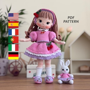 May include: A handmade crochet doll and a small bunny, both in shades of pink and white. The doll wears a pink dress with cherry accents and a matching hat. The bunny is also dressed in pink. The text "PDF PATTERN" is visible.