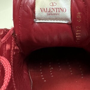 May include: Red leather interior of a shoe with the Valentino Garavani logo and the size 431Y2 40% printed on the inside.