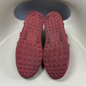 May include: Red leather sneakers with a studded design and the text "VALENTINO" on the soles.