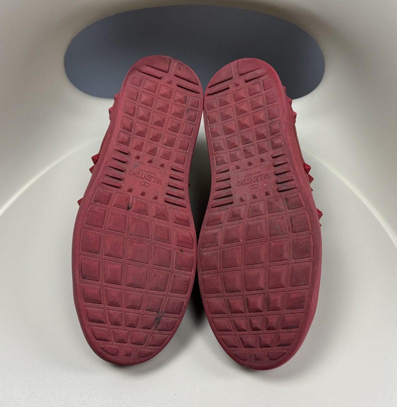 May include: Red leather sneakers with a studded design and the text "VALENTINO" on the soles.