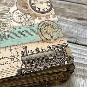 May include: A vintage-style scrapbook with a black and white illustration of a steam train on the cover. The cover also features a blue and green patterned paper with musical notes and clock faces.